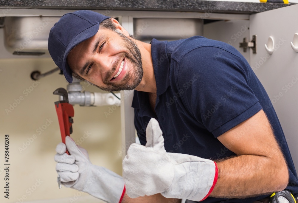 © WavebreakMediaMicro - Plumber smiling at the camera fixing under the sink © WavebreakMediaMicro - Plumber smiling at the camera fixing under the sink