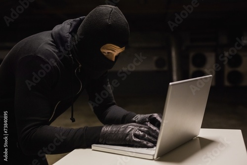 Robber at desk hacking a laptop