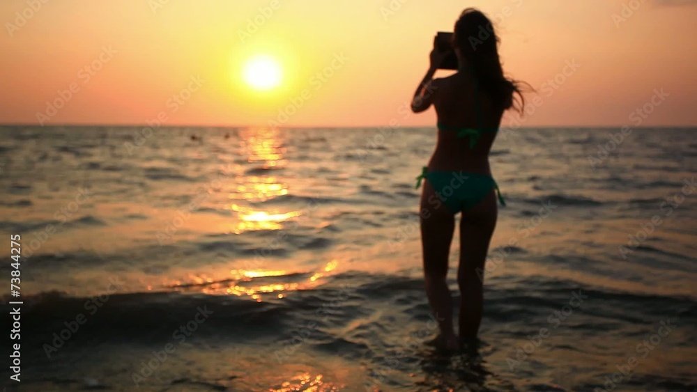 Silhouette of young woman takes a picture from phone on the Silhouette of young woman takes a picture from phone on the