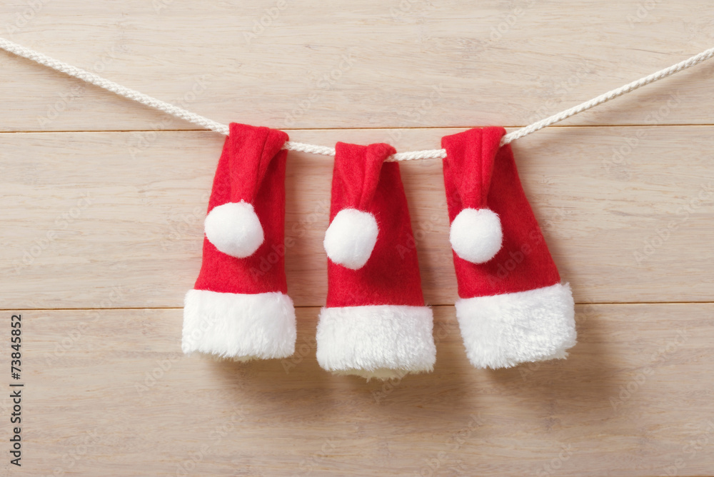 Santa hats on a rope against wooden background Santa hats on a rope against wooden background
