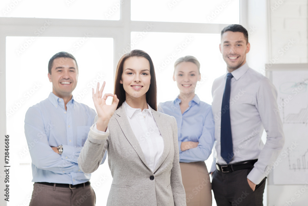 smiling businesswoman showing ok-sign in office smiling businesswoman showing ok-sign in office