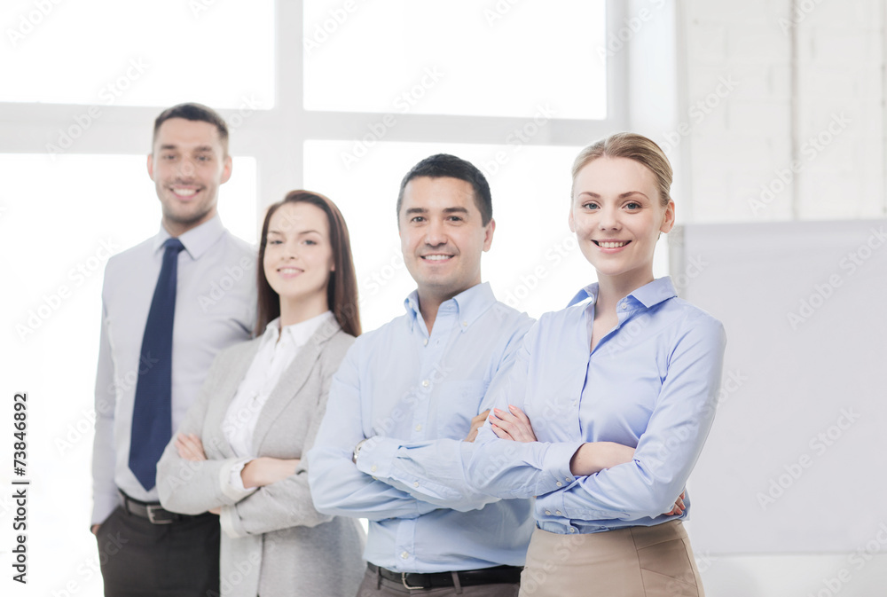smiling businesswoman in office with team on back smiling businesswoman in office with team on back