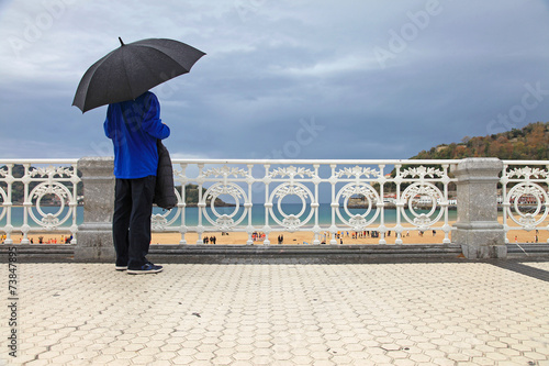 Canvas Print san sebastián donostia hombre con paraguas mirando a la playa de la concha desde