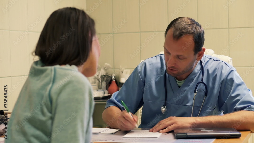 Male doctor writing rx prescription for female patient in hospit Male doctor writing rx prescription for female patient in hospit