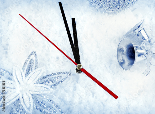 Clock with fir branches and Christmas decorations under snow clo