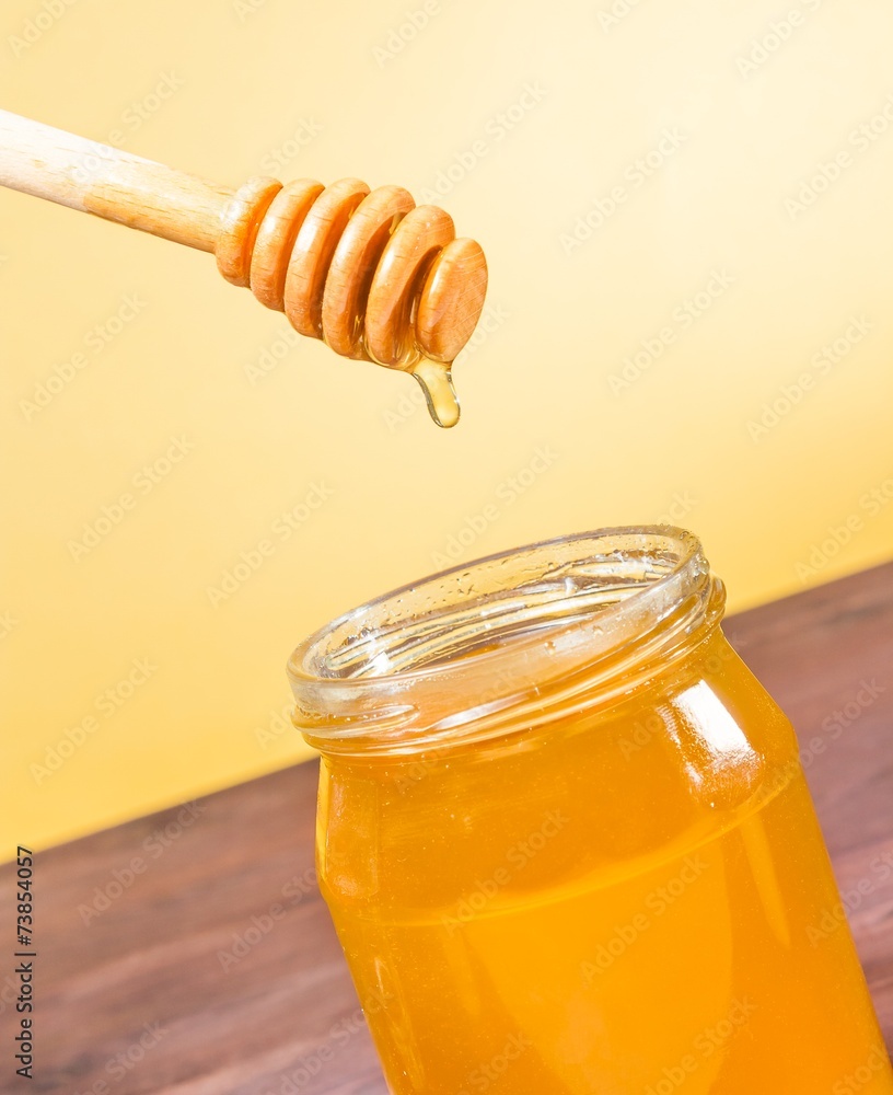 honey jar on wood table and golden background with wooden dipper honey jar on wood table and golden background with wooden dipper