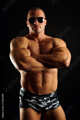 Handsome muscular man in sunglasses posing