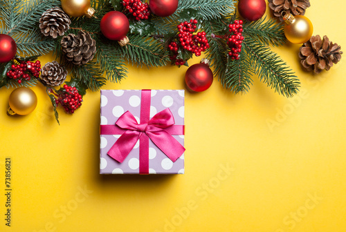 gift box and pine branches on yellow background.