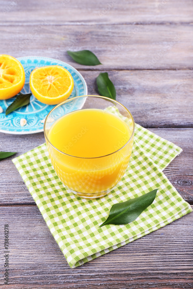 Fototapeta premium Glass of juice and ripe sweet tangerine on wooden table