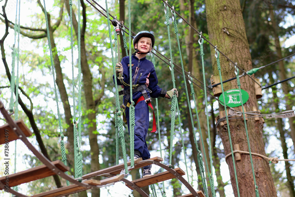 Happy boy climbing in adventure park