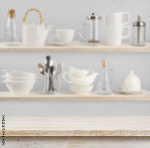 Wooden table over background of shelves with kitchen utensils