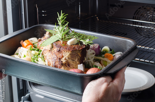 Frau schiebt Braten in den Ofen