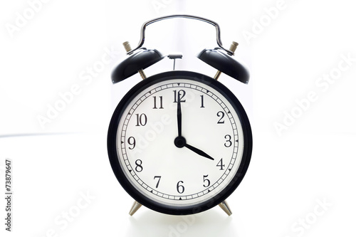 Oldfashioned black glossy alarm clock showing 4 o'clock