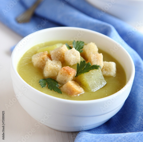 Creamy sweet potato soup with croutons and parsley in white bowl