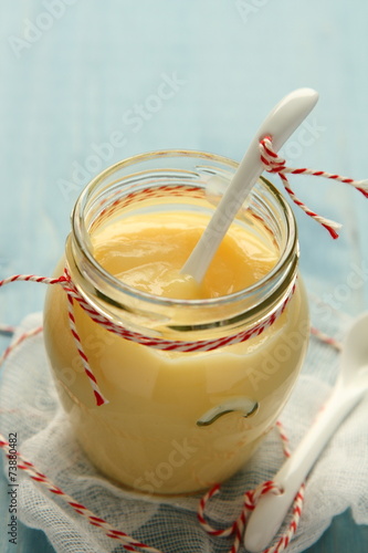 Fotografia Custard cream in glass jar with white ceramic spoon