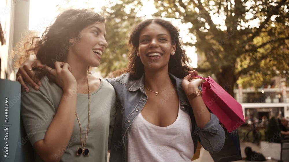 Mixed race girl friends walking in city urban area with shopping Mixed race girl friends walking in city urban area with shopping