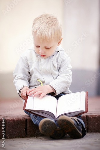 little boy reads a book