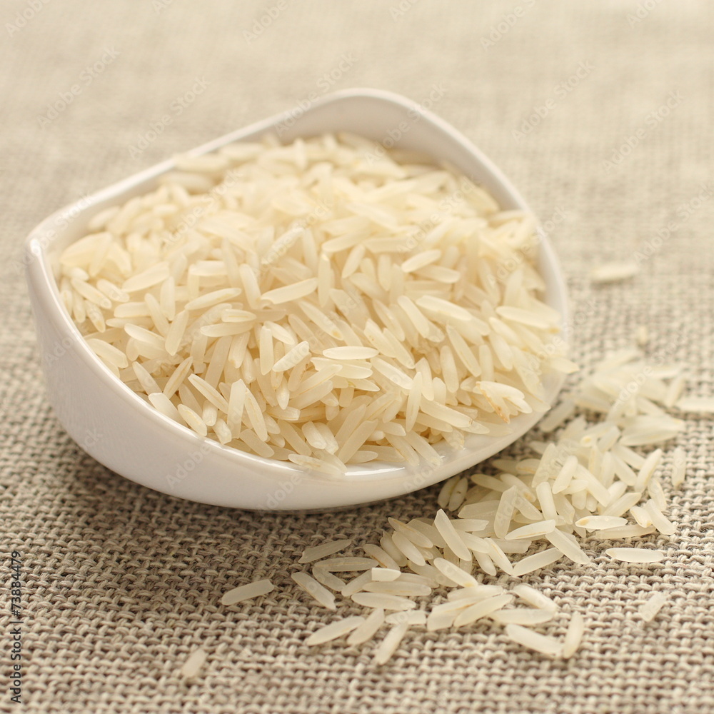Polished long rice grains in white ceramic bowl Polished long rice grains in white ceramic bowl