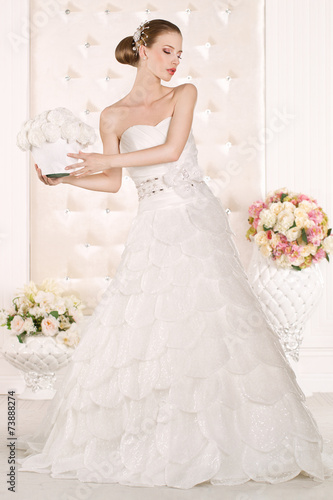 Foto Gorgeous bride with white dress with flowers bouquet