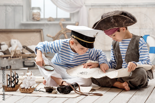 Boys dressed as a pirate captain and read travel map