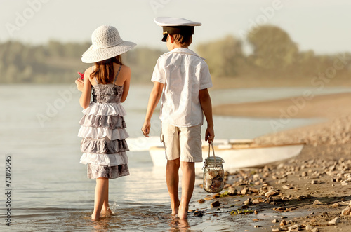 Boy with girl walking along the shore of the lake