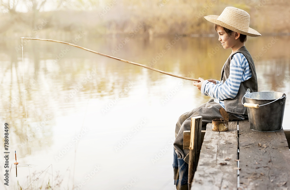Boy fishes on a bridge on the lake Boy fishes on a bridge on the lake