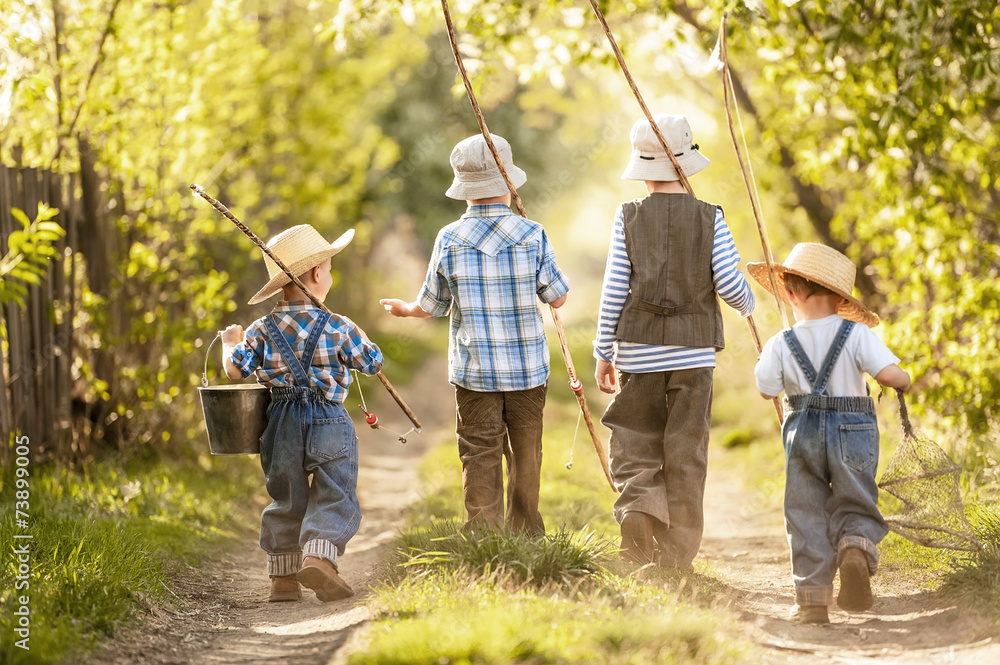 Boys go fishing with fishing rods on a rural street Stock Photo