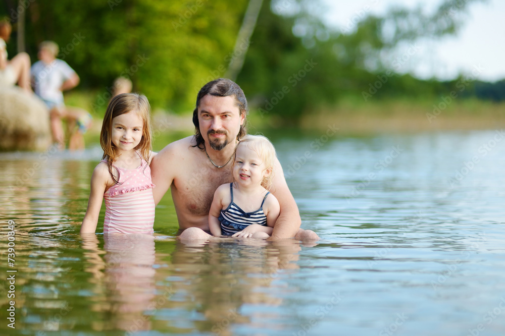 Fototapeta premium Two sisters and their father having fun in a river