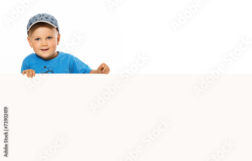 young happy smiling little boy look outs from the blank billboar