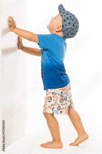 Blond boy pushing he wall white bacground