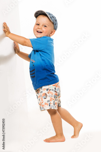 Happy blond boy pushing he wall white bacground