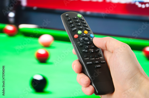 Hand holding remote control in front of tv