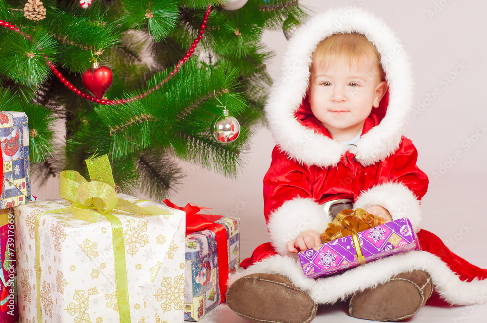 Baby in Santa costume at the Christmas tree with gifts Baby in Santa costume at the Christmas tree with gifts