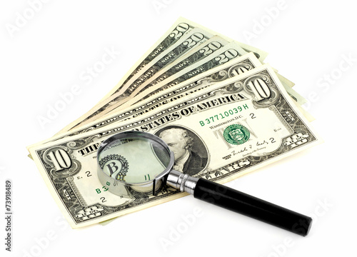 Money and magnifying glass on white background