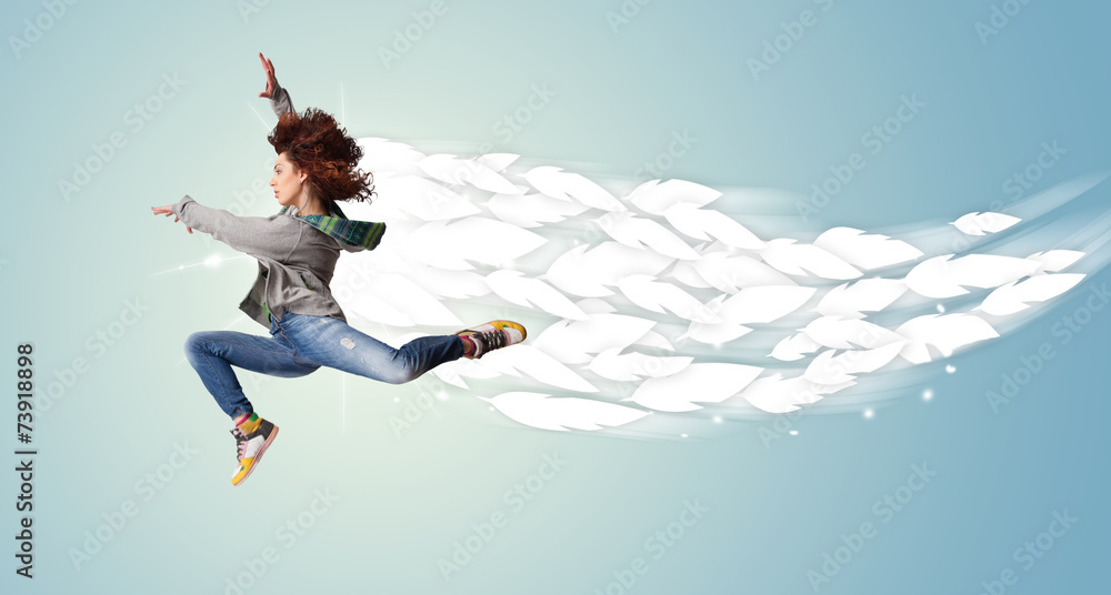 Healthy young woman jumping with feathers around her