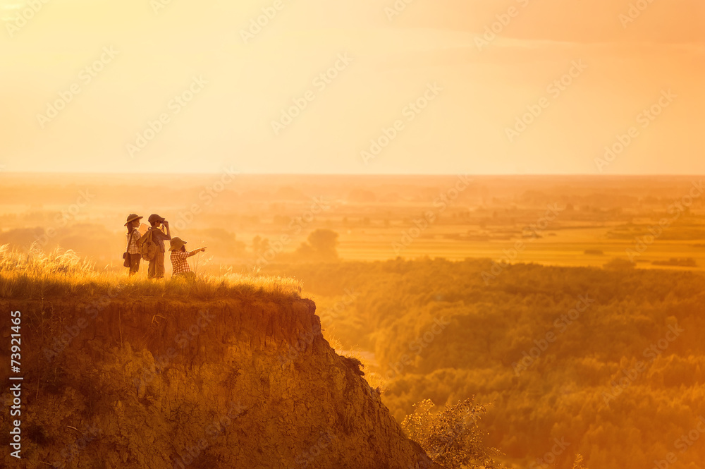 Children with tourists on a cliff at sunset