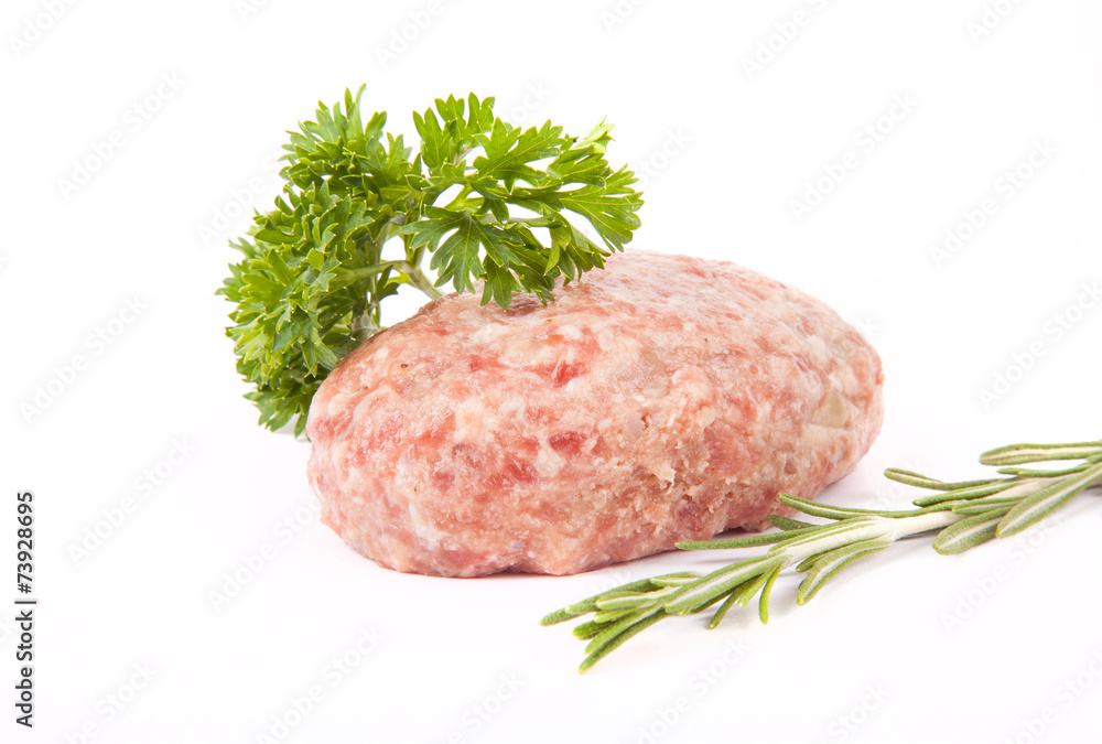 raw meat cutlet with a sprig of parsley and rosemary on a white raw meat cutlet with a sprig of parsley and rosemary on a white