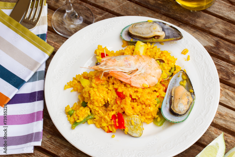 Paella served in plate on wooden table Paella served in plate on wooden table