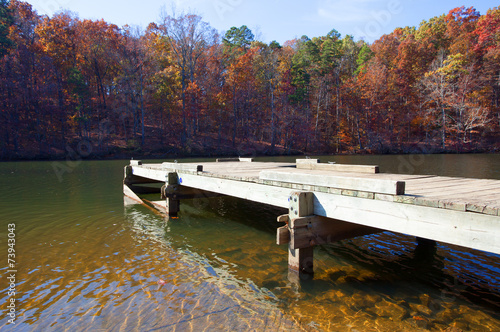 Small wood boat dock and forest behind in full fall colors in North Carolina photo