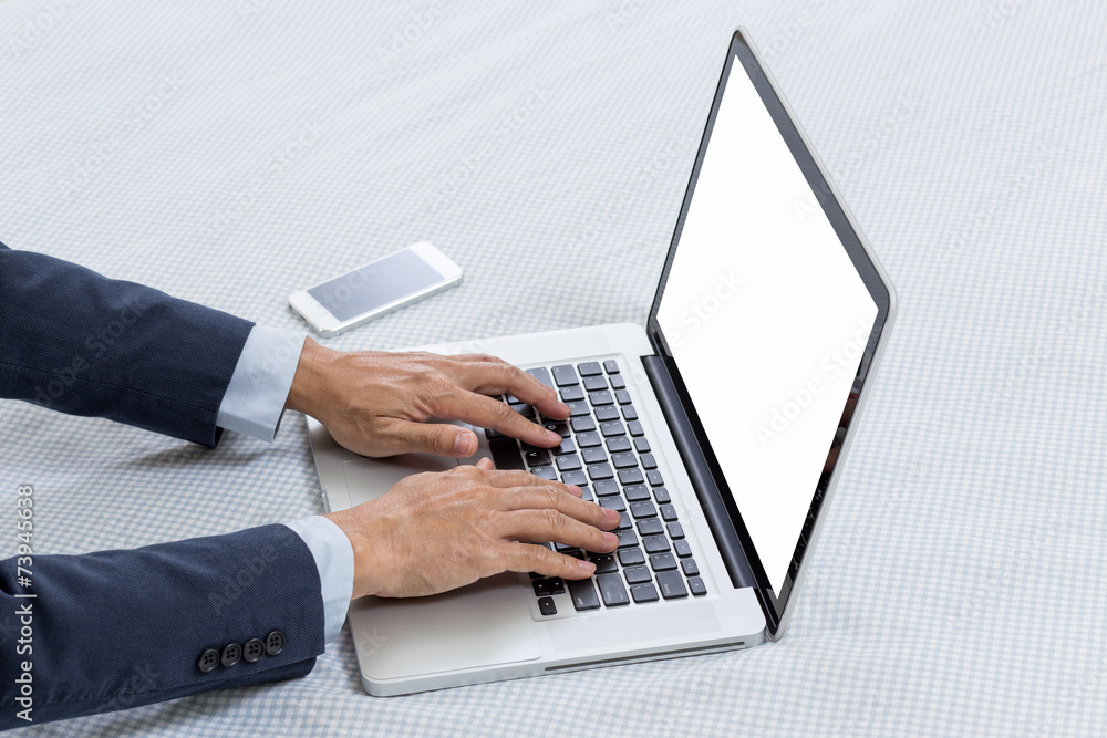 Laptop computer on bed with businessman hands Laptop computer on bed with businessman hands