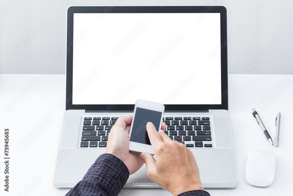 Man hand holding mobile phone with blank screen laptop computer Man hand holding mobile phone with blank screen laptop computer