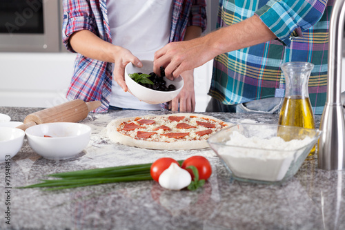 Close-up of putting ingredients for pizza