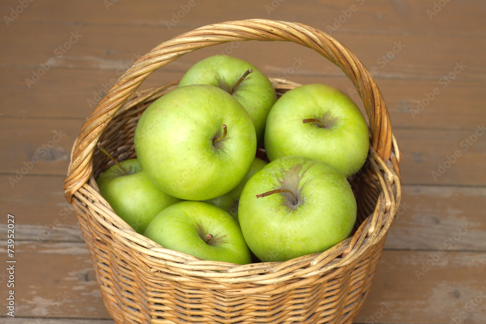 Ripe green apples in wicker basket on timber background Ripe green apples in wicker basket on timber background