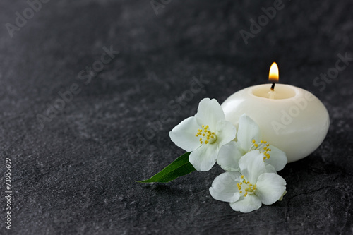 Jasmine flowers and burning candles for spa on a black