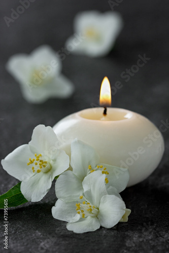 Jasmine flowers and burning candles for spa on a black
