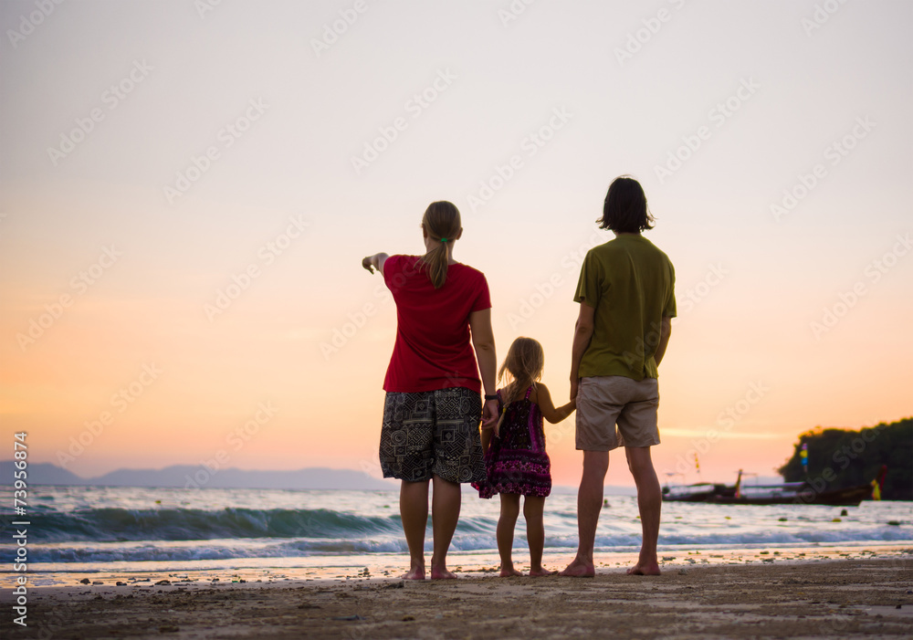Family with mother, father and daughter on tropical sunset beach