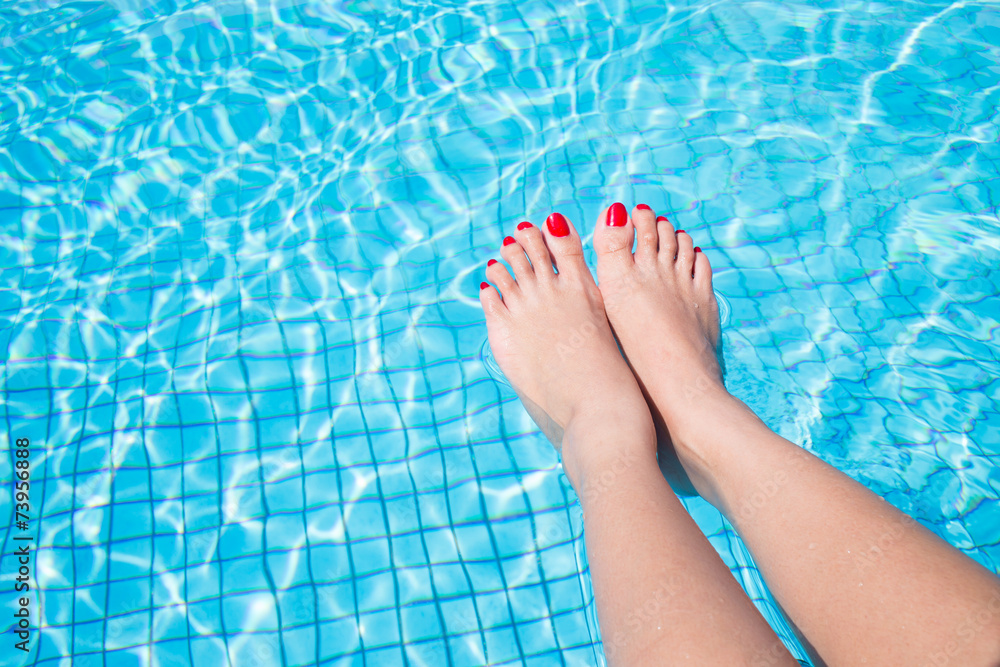 woman legs with red nail in swimming pool