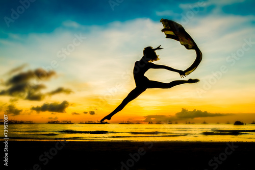 silhouette of jumping girl on tropical sunset sea and sky backgr