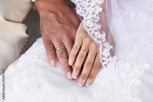 Couple holding hands against wedding dress