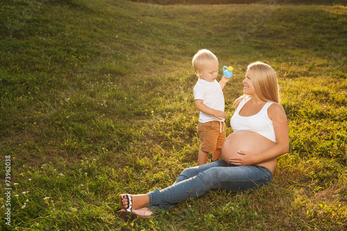 Cute little boy watering his mother's belly.